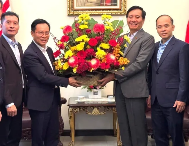 Lao Ambassador to Malaysia Thepthavone (L) presents a bouquet of fresh flowers to Vietnamese Ambassador Ding Ngoc Linh. (Photo: VNA)