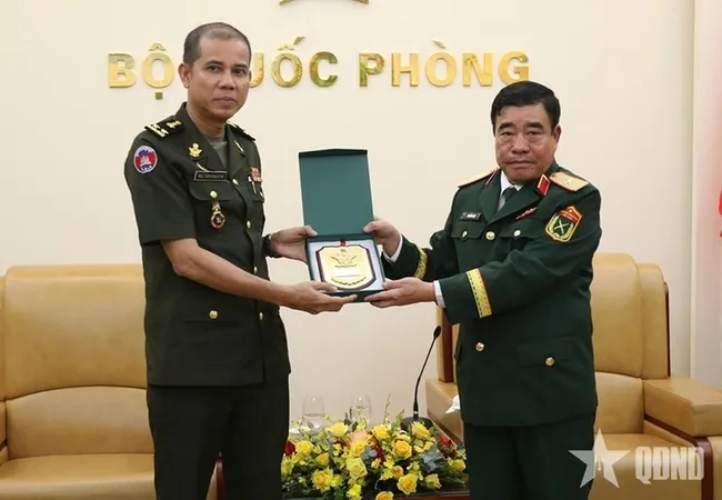 Major General Nguyen Ba Luc (R) presents a gift to Lieutenant General Nim Balene. (Photo: qdnd.vn)