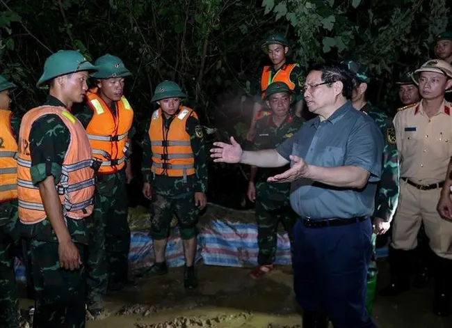 Prime Minister Pham Minh Chinh visits the forces working to reinforce the Cau River embankment, emphasising the need to ensure the dike’s safety. (Photo: VNA)