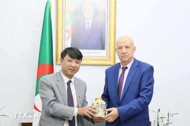 Deputy Editor-in-Chief of the Communist Review Nguyen Ngoc Ha (L) presents a gift to Secretary General of the National Liberation Front (FLN) of Algeria Abdelkrim Benmbarek (Photo: VNA)