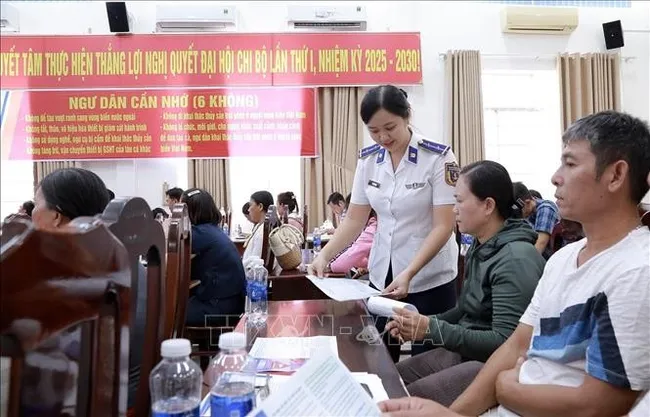 Officers of Coast Guard Region 4 distribute information leaflets to local fishermen. (Photo: VNA)