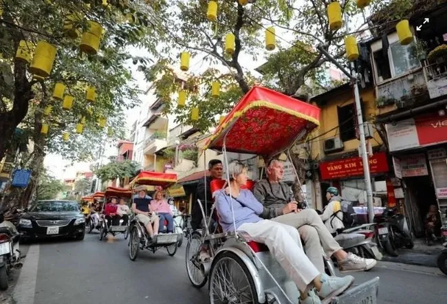 Foreign visitors explore Hanoi’s old quarters by cyclo, admiring the city’s timeless beauty. (Photo: VNA)