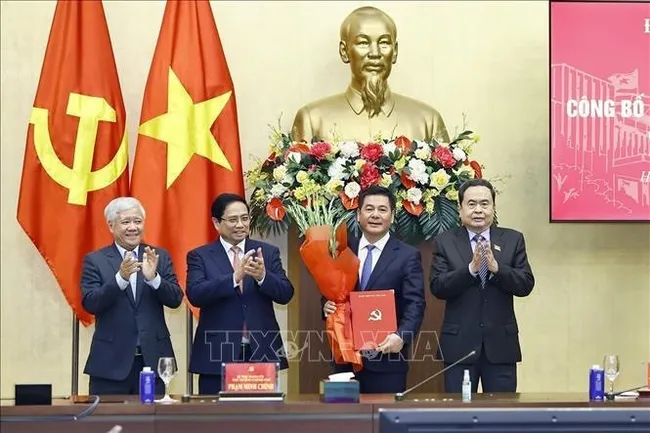 Prime Minister Pham Minh Chinh (second from left) and National Assembly Chairman Tran Thanh Man (far right) present the appointment decision and congratulatory flowers to Nguyen Hong Dien. (Photo: VNA)
