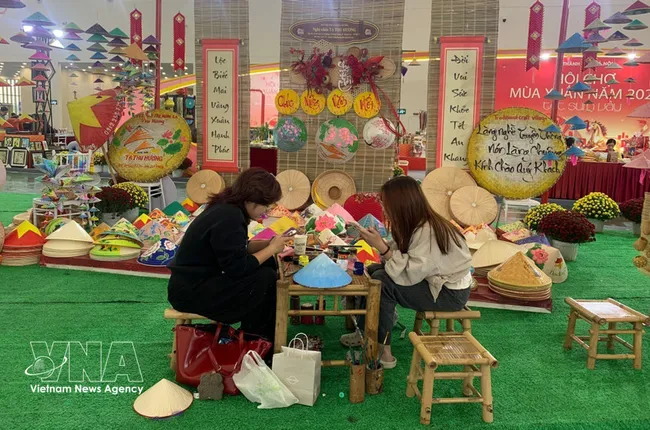 Young visitors come to enjoy their time at the booth of Chuong conical hat making village at the Glorious Spring Fair 2026 in Hanoi (Photo: VNA)