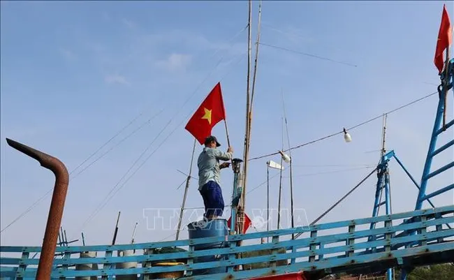Fishermen raise the national flag before heading out to the sea to affirm Vietnam’s sovereignty over its seas and islands. (Photo: VNA)