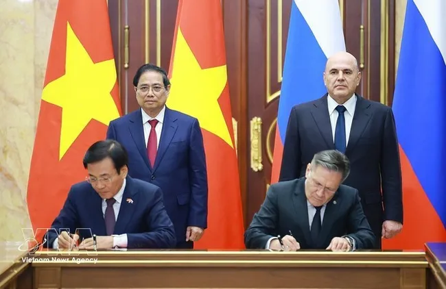 Vietnamese PM Pham Minh Chinh (standing, left) and his Russian counterpart Mikhail Mishustin (standing, right) witness the signing of the agreement between the two governments on cooperation in building a nuclear power plant on the territory of Vietnam. (Photo: VNA)
