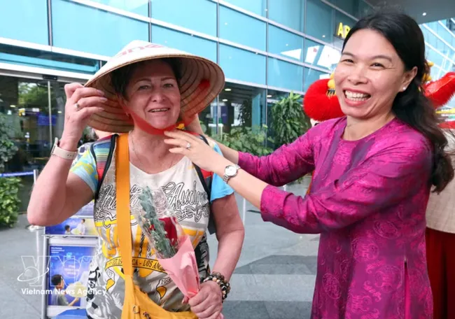 A representative of Anex Tour Vietnam presents a conical hat to the first passengers arriving in Da Nang from Vladivostok. (Photo: VNA)