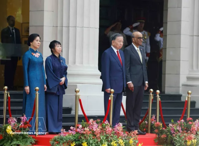 Party General Secretary and State President To Lam and Singaporean President Tharman Shanmugaratnam, together with their spouses, stand on the podium of honour as military bands perform the national anthems of Vietnam and Singapore at the welcome ceremony on May 29 morning. (Photo: VNA)