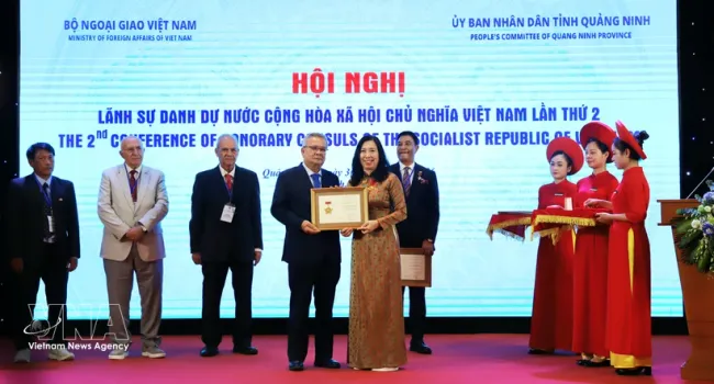 Deputy Minister of Foreign Affairs Le Thi Thu Hang (R) presents the 
