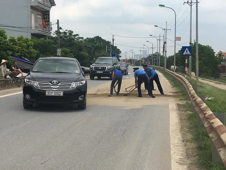 Thanh tra giao thông dọn cát rơi vãi giữa đường Hà Nội - Ảnh 1.