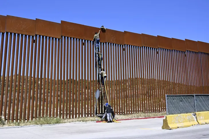 Người di cư bắc thang vượt qua hàng rào biên giới Mỹ - Mexico - Ảnh 1. Người di cư bắc thang vượt qua hàng rào biên giới Mỹ - Mexico - Ảnh 1.
