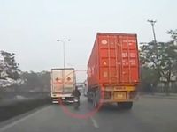 Xe máy liều lĩnh 'len' giữa xe tải và container