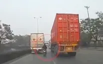 Xe máy liều lĩnh "len" giữa xe tải và container