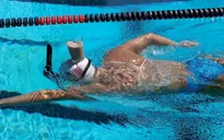 Nhà vô địch Olympic bơi với ly sữa ở trên đầu