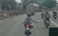 Người đàn ông điều khiển xe máy bằng một tay, lạng lách trên đường