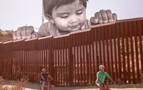 Chân dung bé trai di cư khổng lồ ngó qua biên giới Mỹ - Mexico