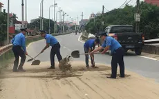 Thanh tra giao thông dọn cát rơi vãi giữa đường Hà Nội