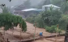 Người đàn ông liều mình băng qua cầu treo mặc nước lũ chảy xiết