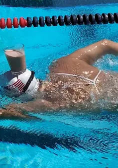 Nhà vô địch Olympic bơi với ly sữa ở trên đầu
