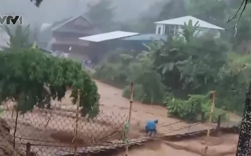 Người đàn ông liều mình băng qua cầu treo mặc nước lũ chảy xiết