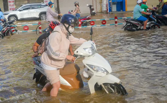 Tình nguyện viên dầm mưa, lội nước giúp người dân trong triều cường